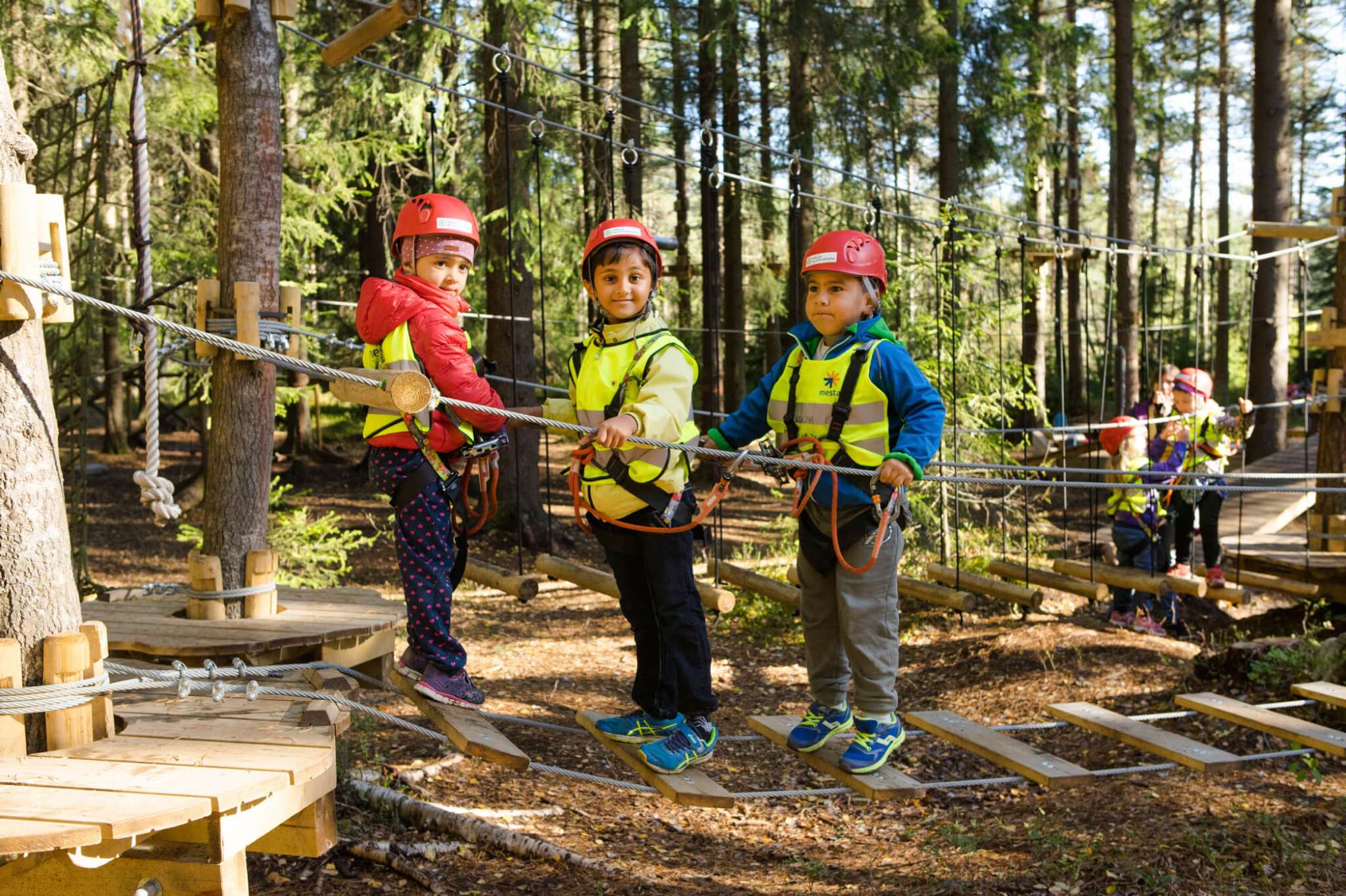Barnehagebarn leker på taubro i klatrepark. Foto