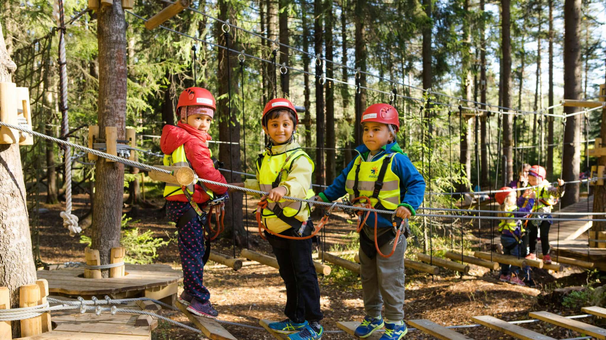 Barnehagebarn leker på taubro i klatrepark. Foto