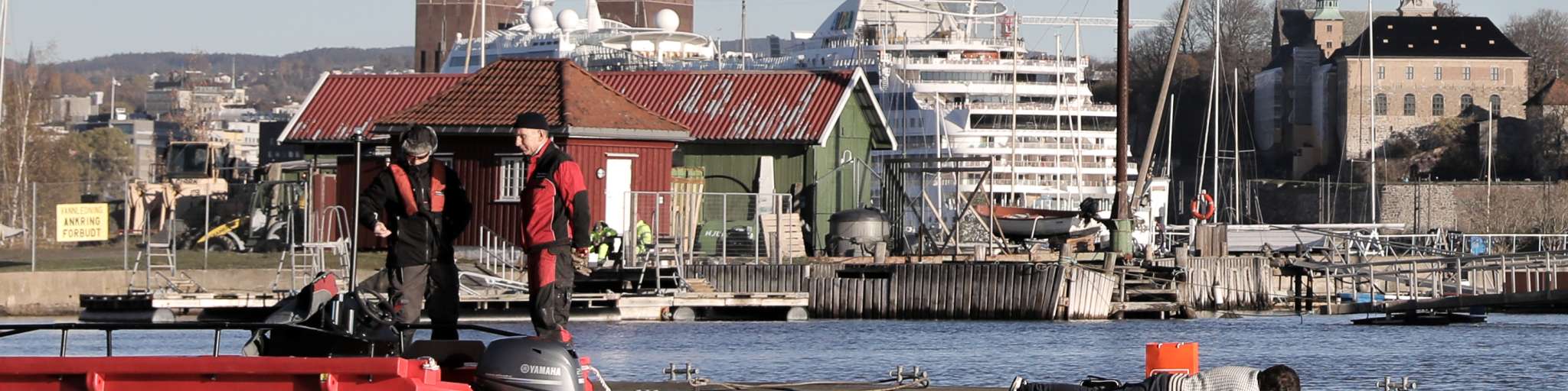 Mann monterer noe på brygge foran Akershus festning