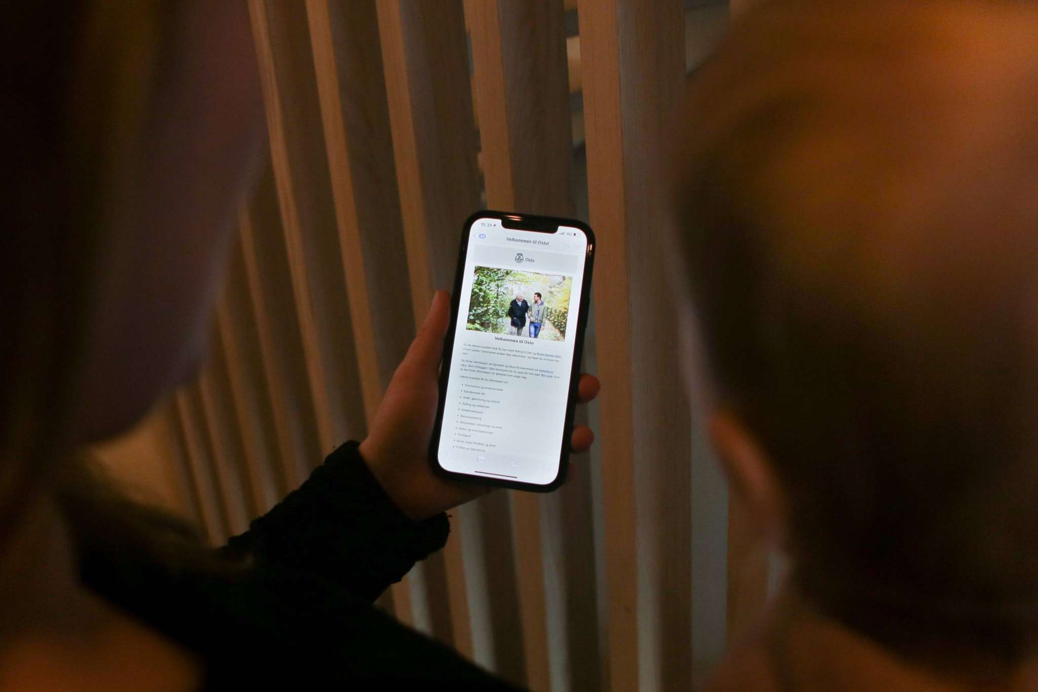 To personer sett bakfra ser på mobil med Velkommen til Oslo-melding