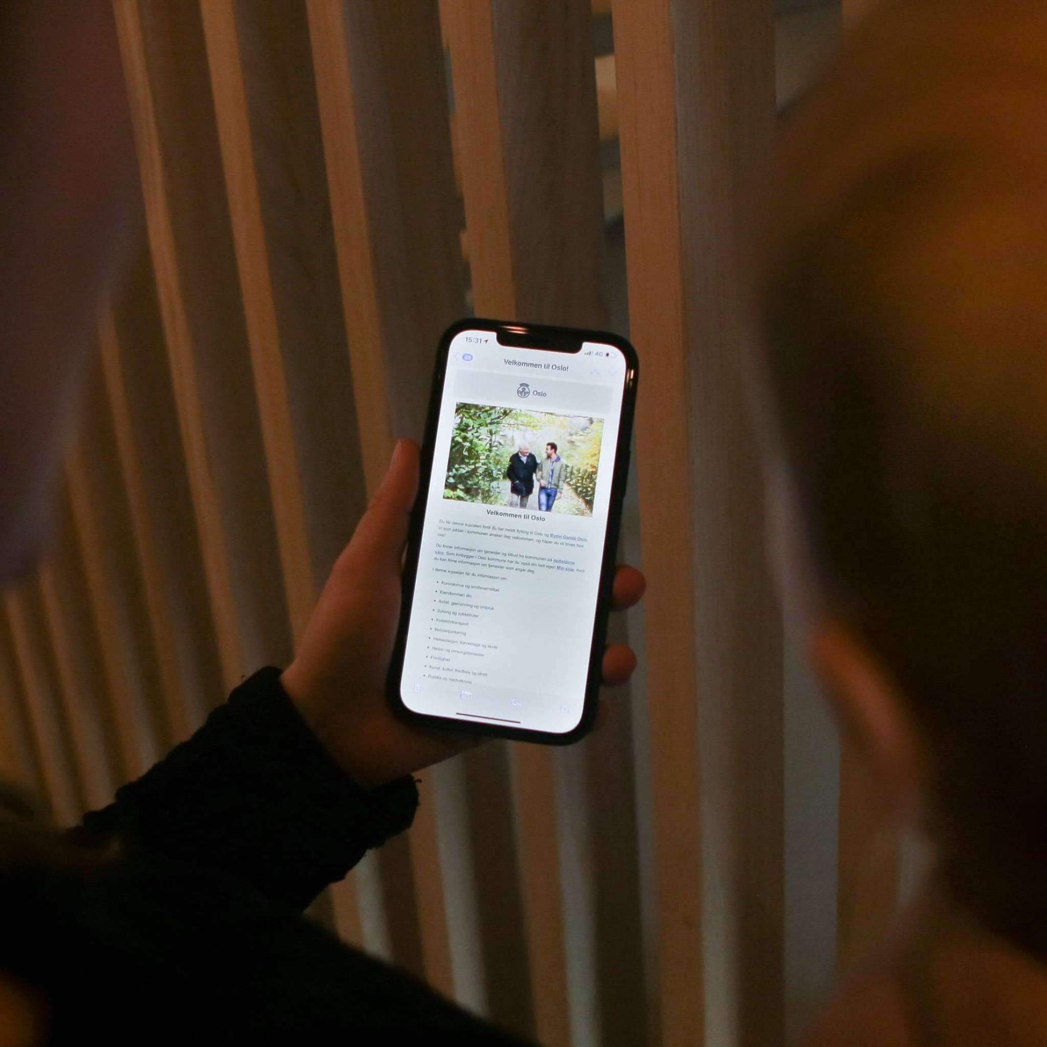 To personer sett bakfra ser på mobil med Velkommen til Oslo-melding