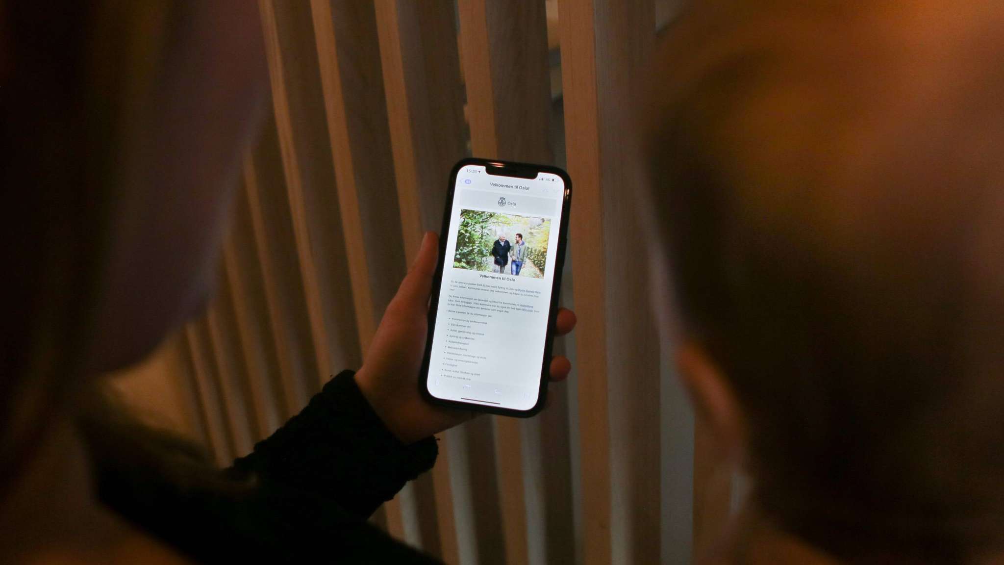 To personer sett bakfra ser på mobil med Velkommen til Oslo-melding