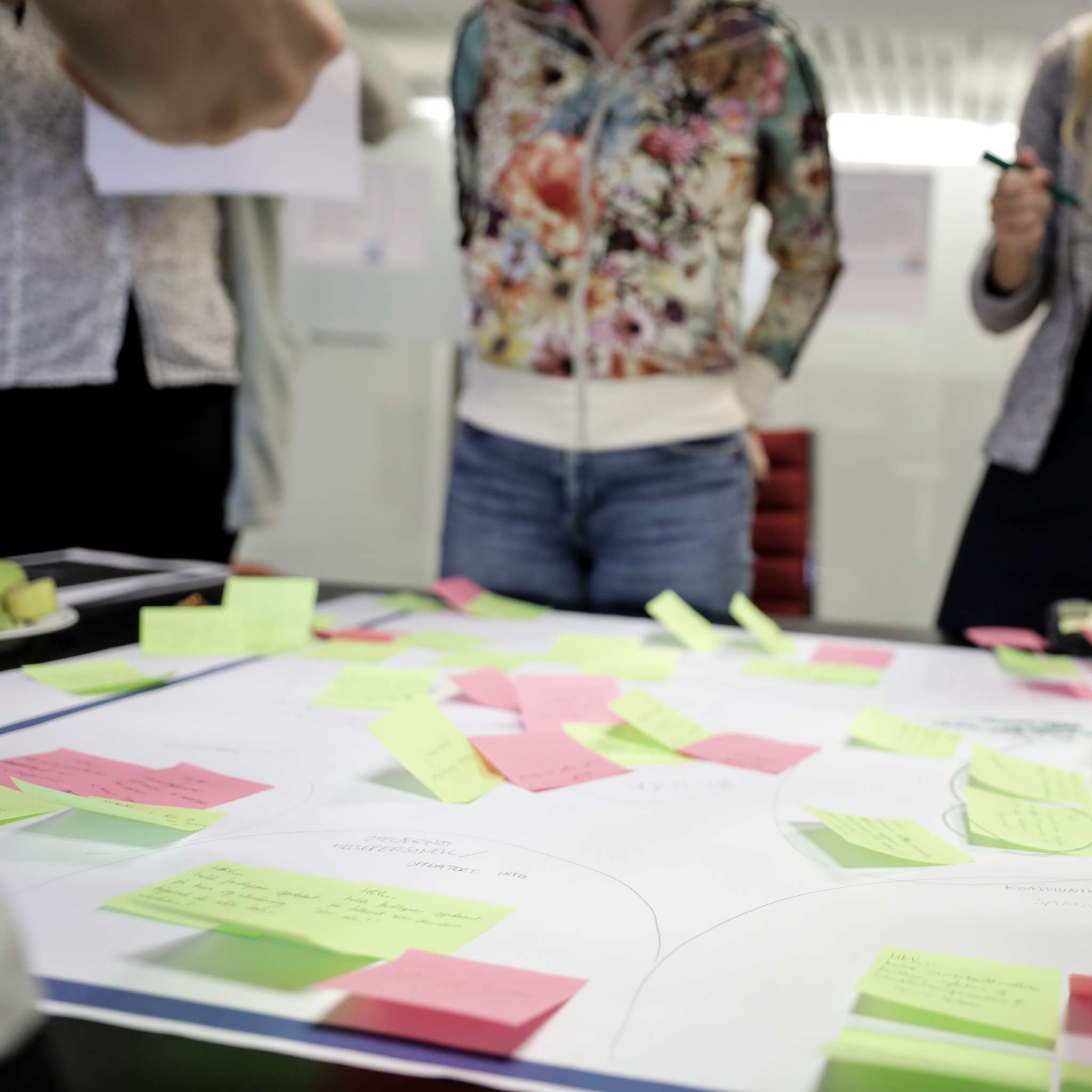Ansatte diskuterer bak et arbeidsbord